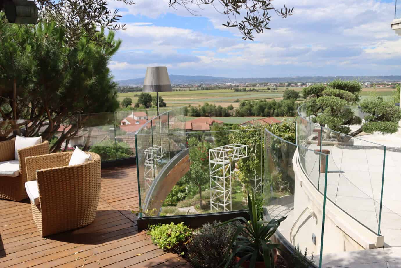Barandilla de vidrio SADEV SABCO instalada en terraza exterior residencial con vistas al paisaje y tarima de madera