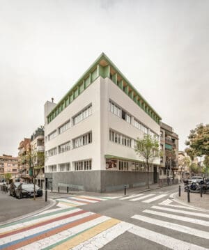 Vista exterior en esquina de la Escuela Santa Eulàlia de Cornellà tras la rehabilitación de Taller SAU, con nueva remonta verde y zócalo de piedra