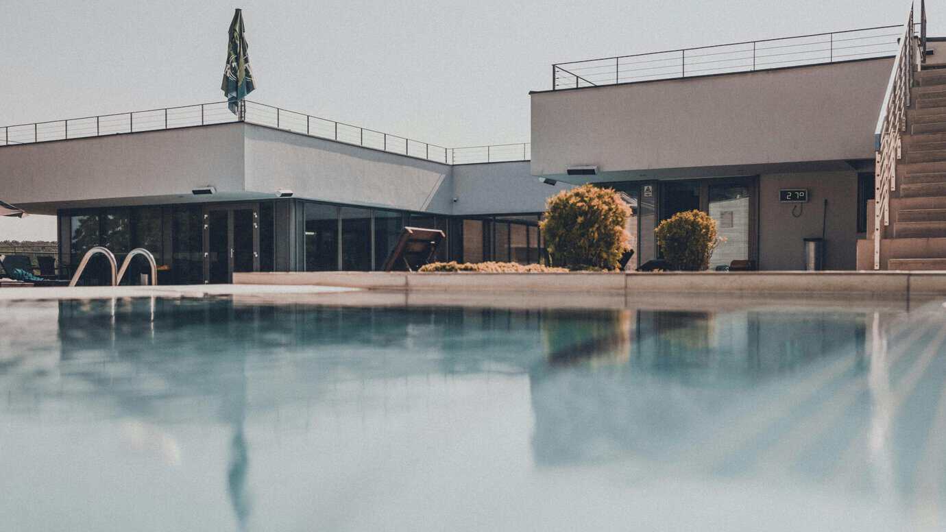 Terraza exterior con pavimento técnico junto a piscina de vivienda moderna con grandes aperturas y continuidad visual interior-exterior