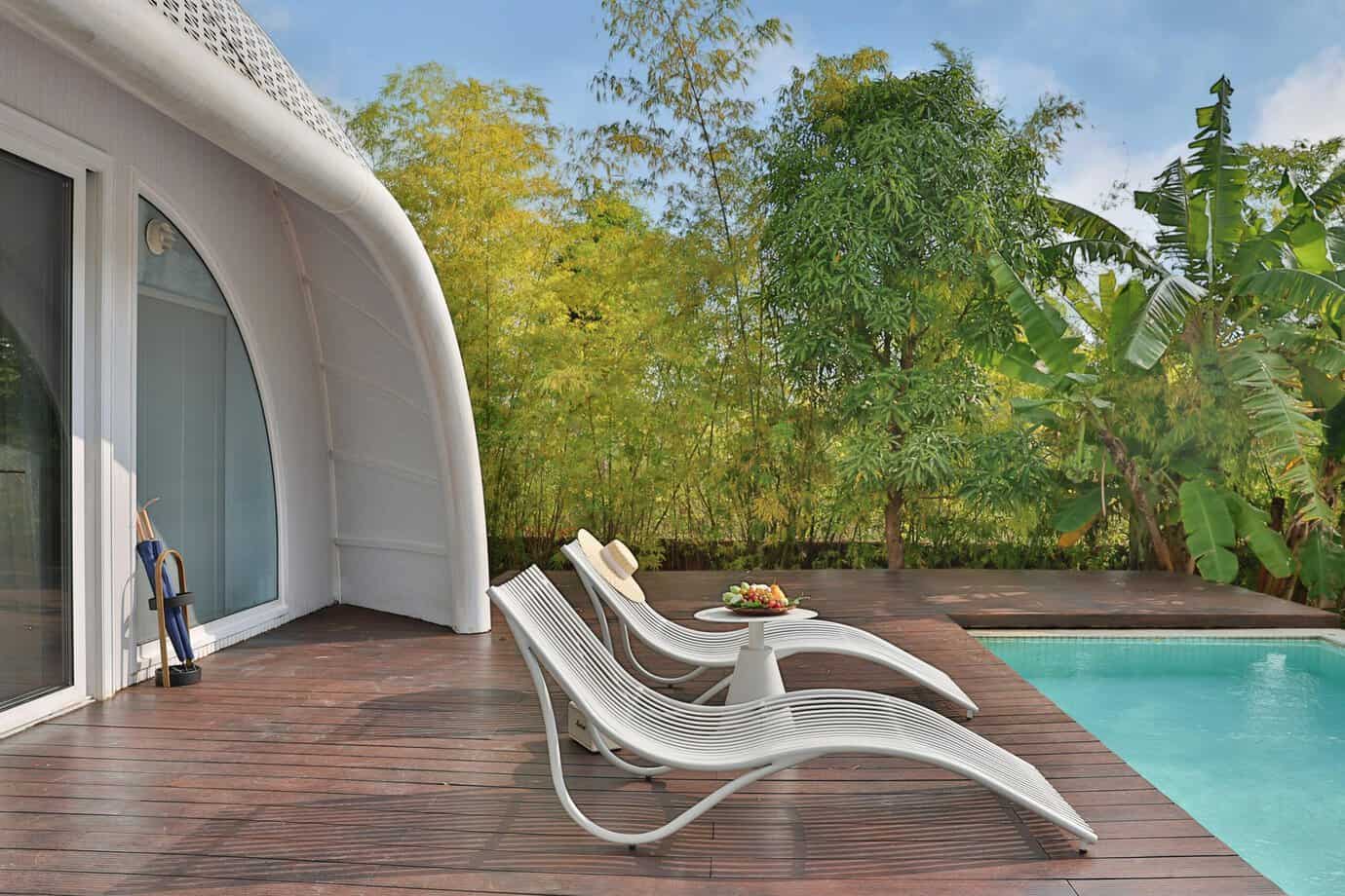 arima de madera WPC junto a piscina exterior con tumbonas de diseño y vegetación tropical