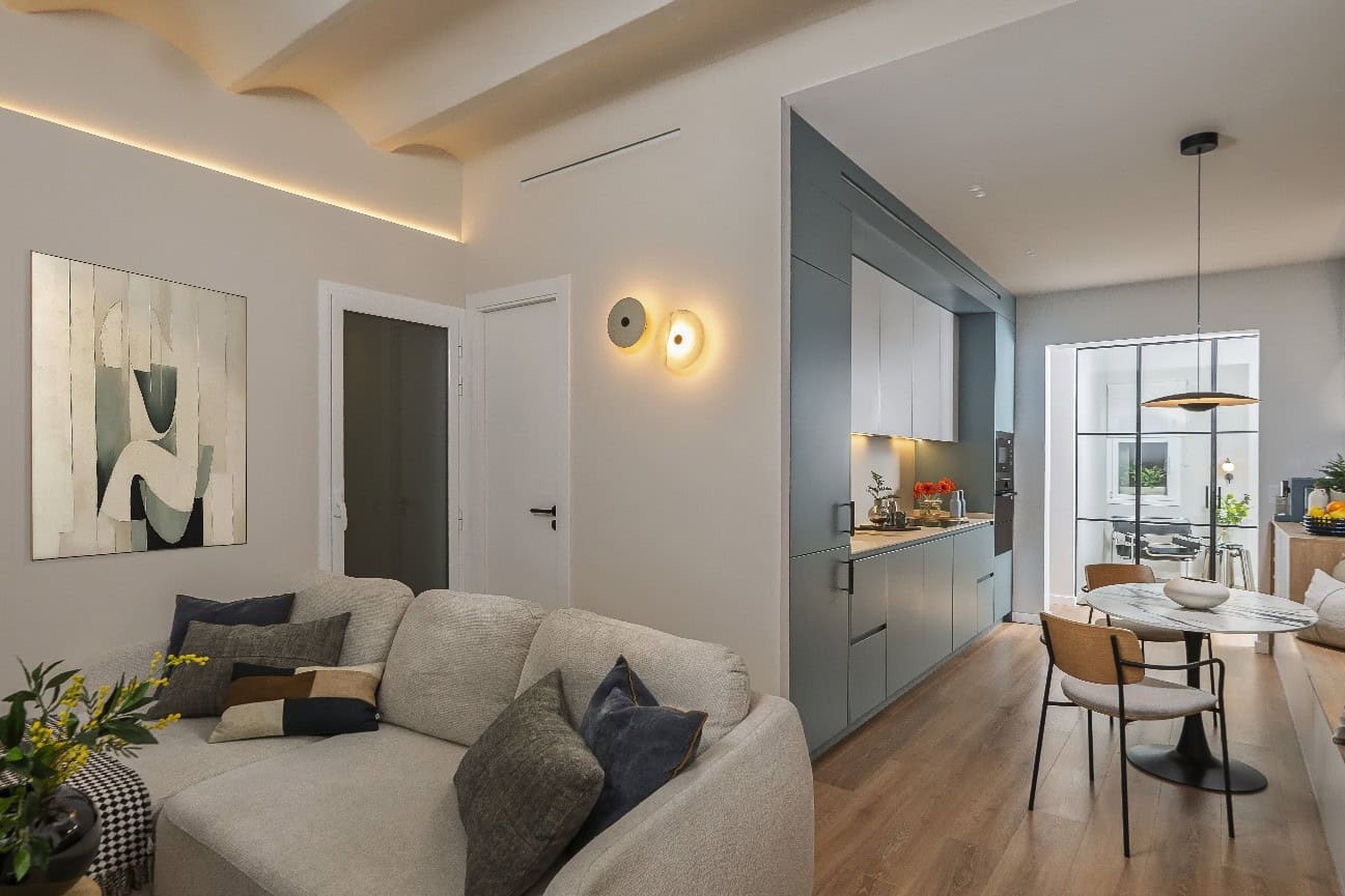 Salón reformado de 60 m² con bóveda catalana iluminada con tira LED, cocina a medida en azul petróleo y zona de comedor en vivienda de Barcelona diseñada por ACP Interiors