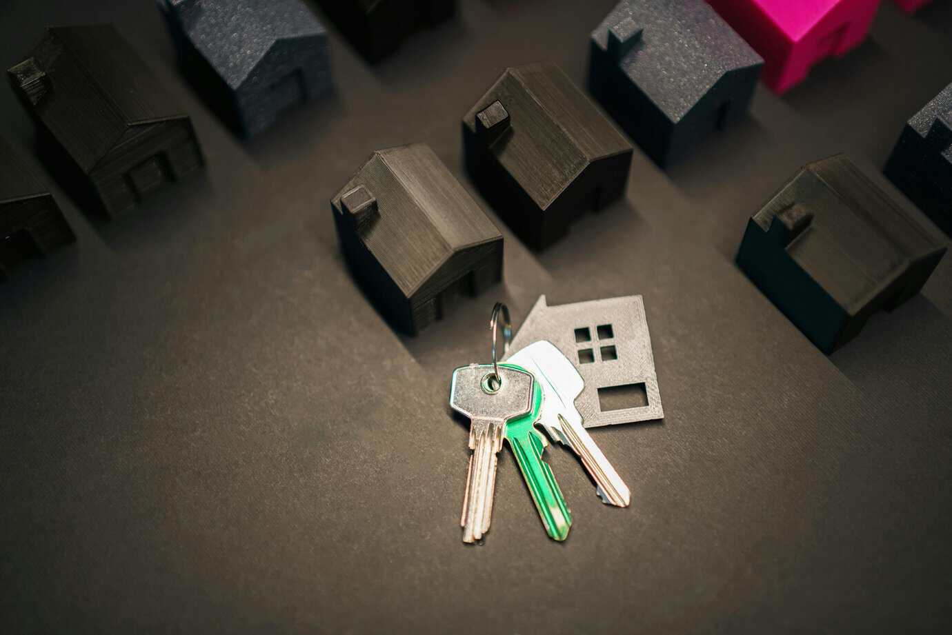 Llaves con llavero en forma de casa junto a maquetas de viviendas, representando la compra de inmuebles con criptomonedas en España